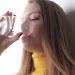 Woman in a yellow sweater drinks water from a transparent glass.